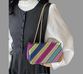 Metallic Colorburst Handbag with multicolored design and metallic finish, worn by a model in a black dress.