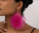 Pink floral design earrings on a woman's ear.