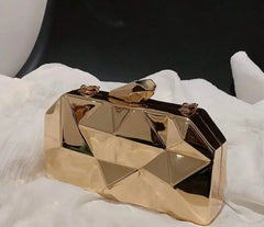 Gold geometric Reflections Clutch on white fabric.