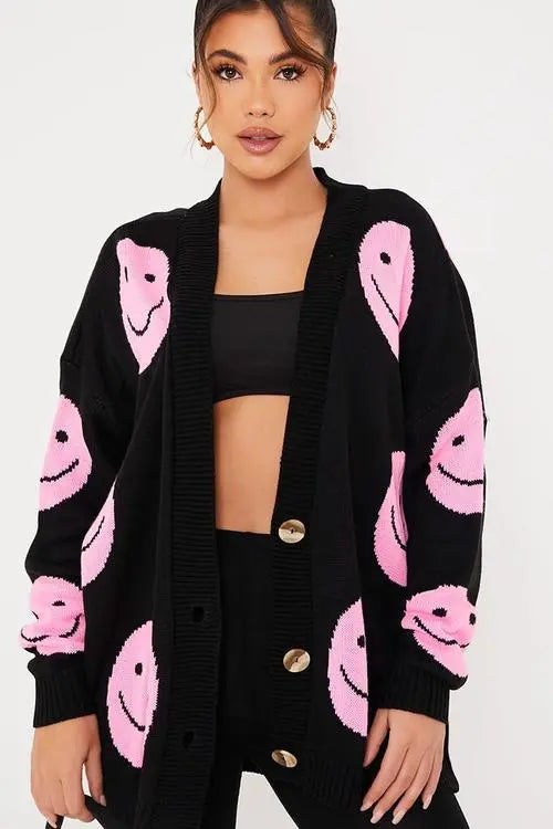 Black cardigan with pink smiley faces and button detail.
