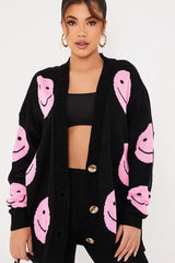 Black cardigan with pink smiley faces and button detail.